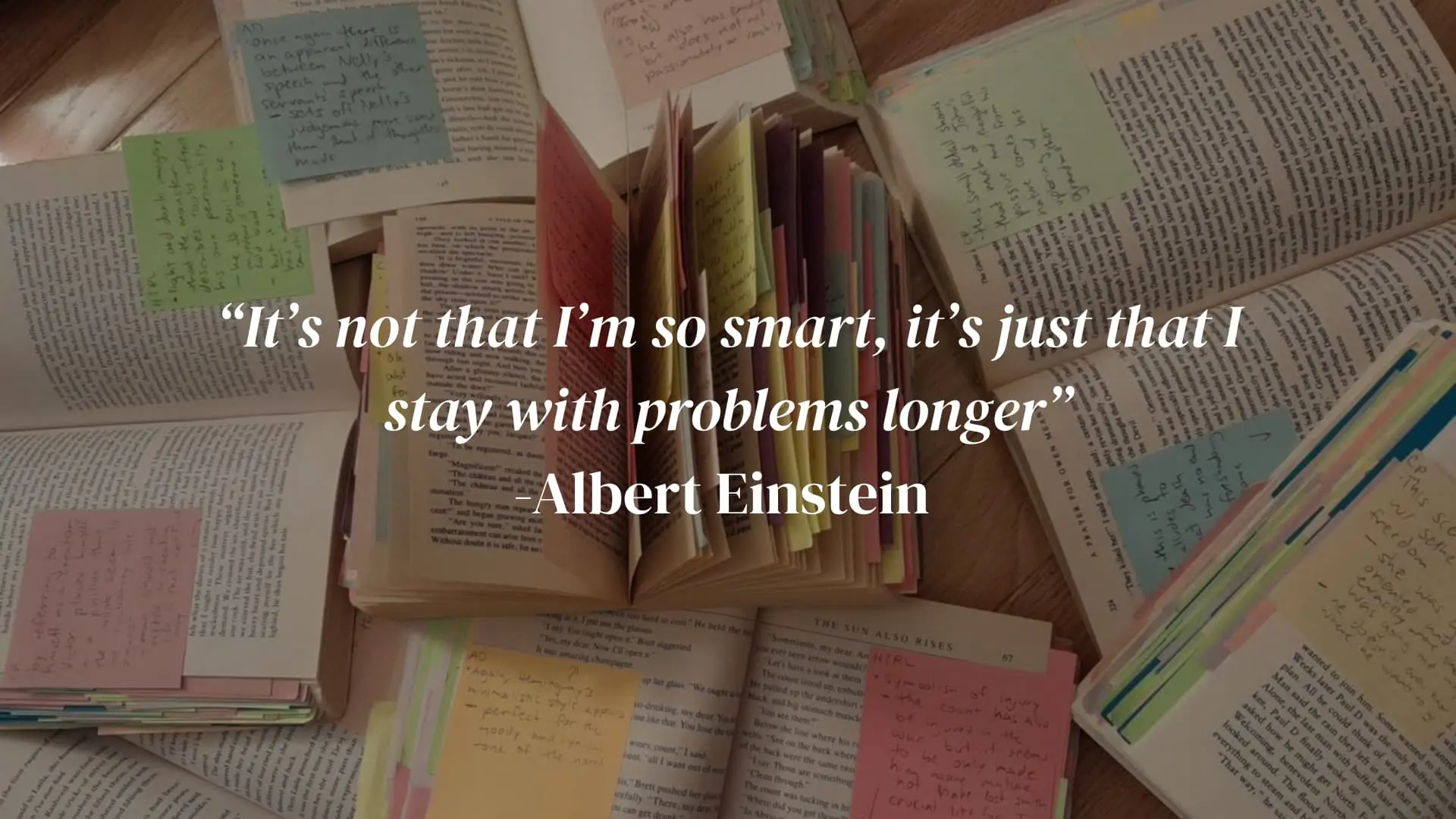 open books and colorful sticky notes spread across a desk with an Albert Einstein quote on studying
