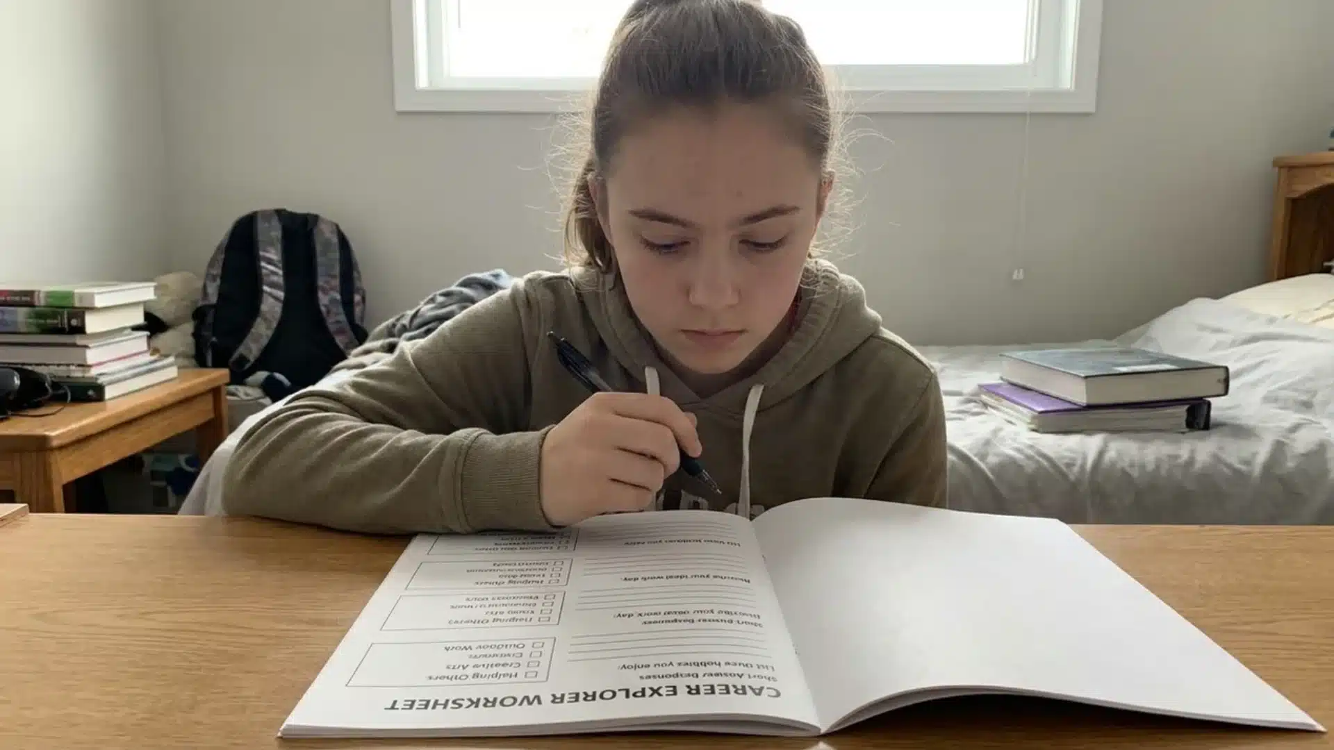 student completing a career explorer worksheet at a desk with books and study materials nearby