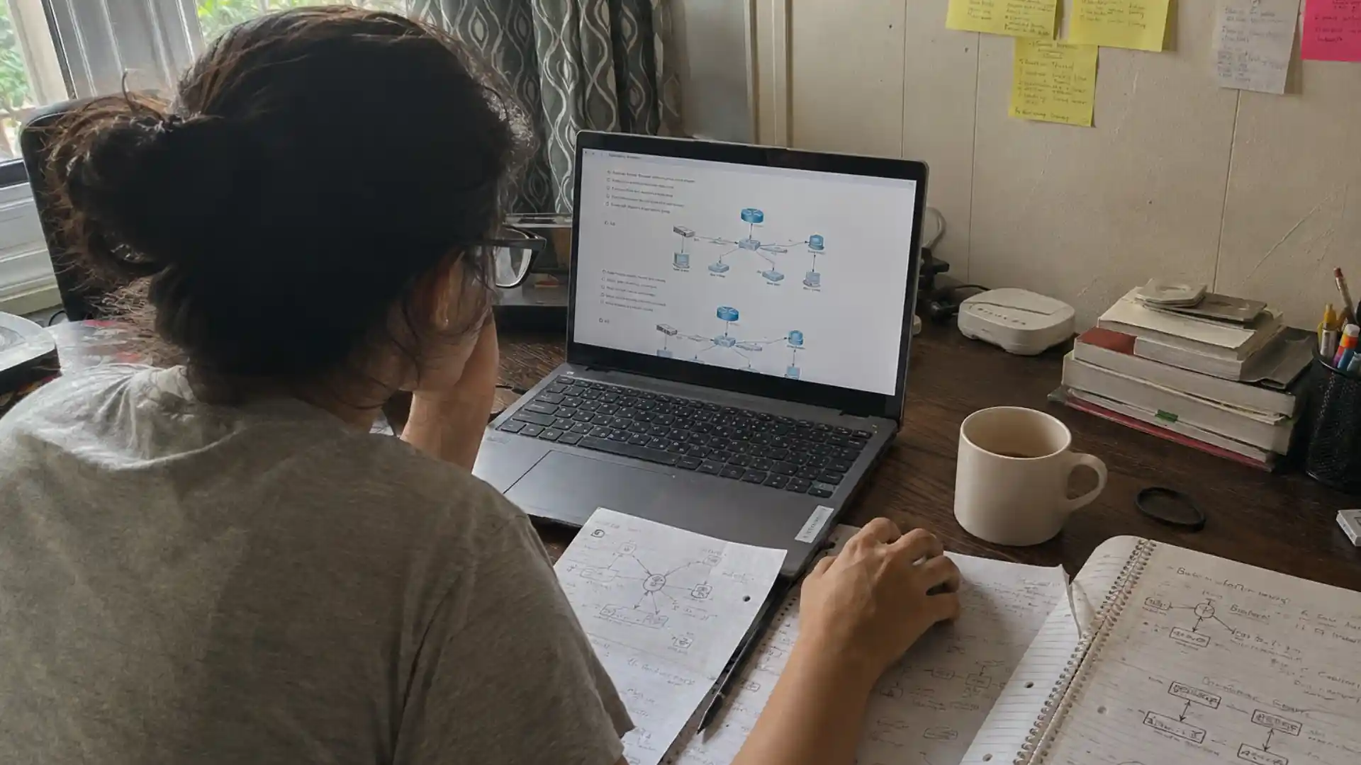 person studying network diagrams and ccna quiz questions at a home desk