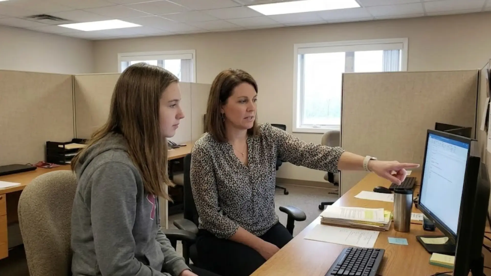 professional guiding a student through an online career planning exercise at a desktop computer