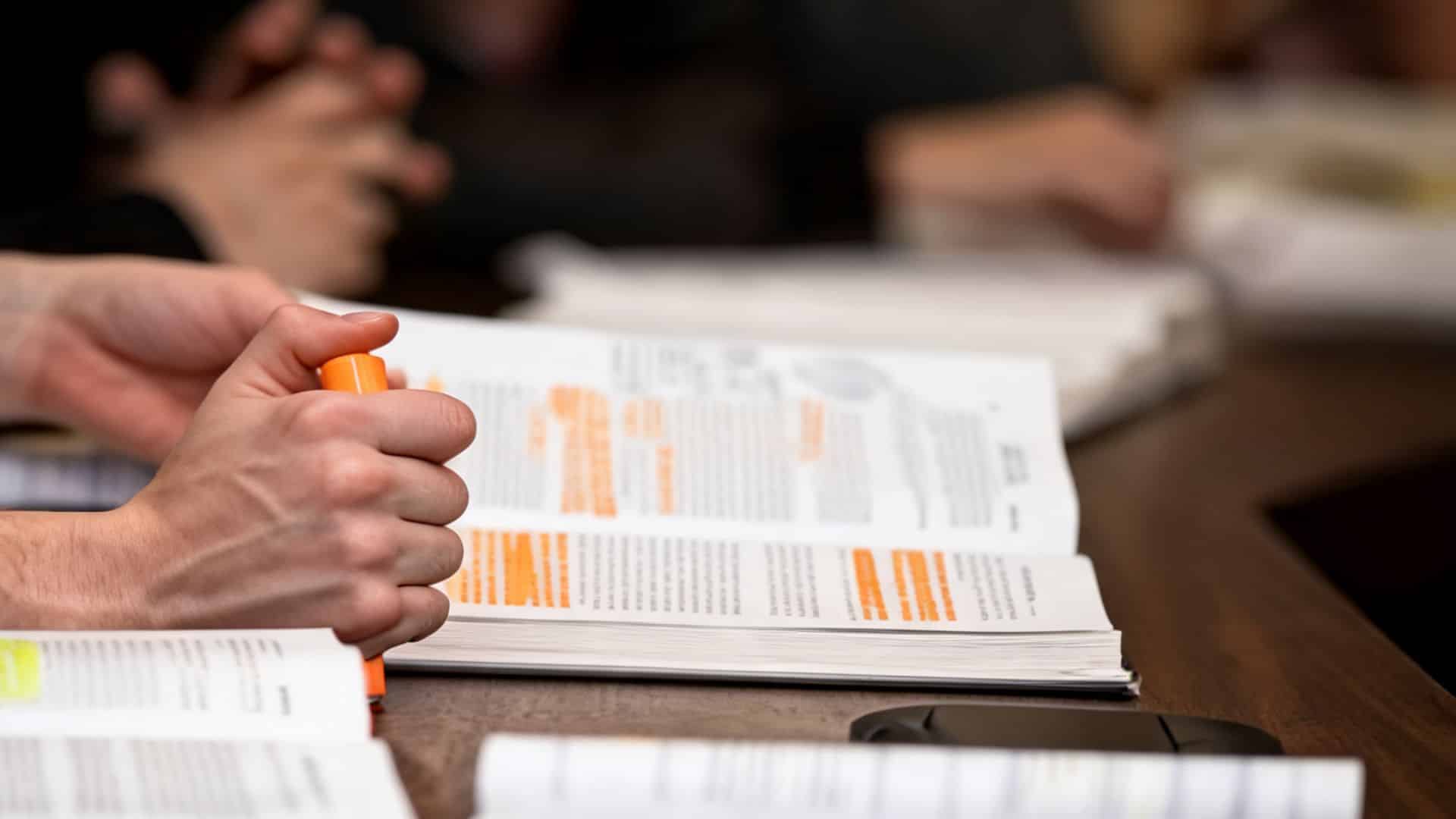 students reviewing highlighted study books with colorful markers during a focused group study session